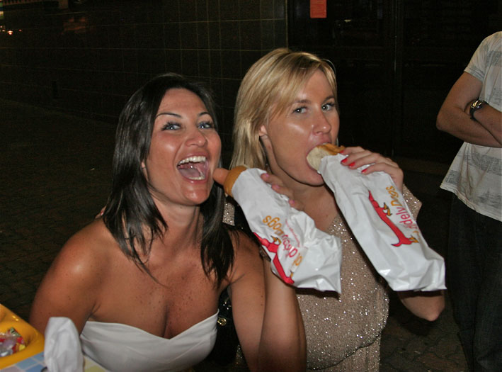 Customer biting into a gourmet hot dog wrapped in HDD packaging
